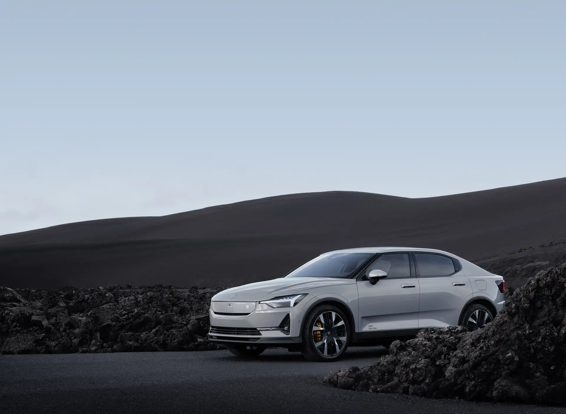 Ein Polestar 2 in der Frontansicht auf einer Landstraße in bergigem Gebiet.